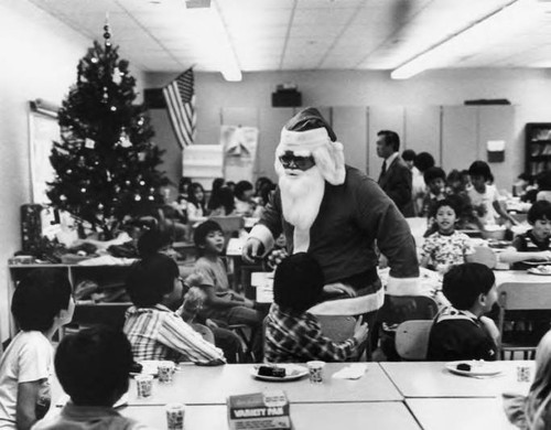 Gerald Jann dressed as Santa Claus entertaining a class at the Castelar School