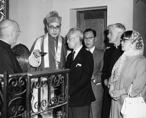 Photo of Cardinal Paul Yu Pin performing a baptism as Stanley and Lily Chan bear witness