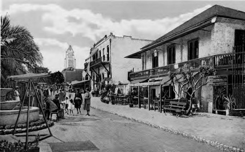 3X5 postcard of Olvera Street looking south- can see City Hall in background. Pelanconi House and Sepulveda House on right (west) side. Palm tree and fountain on left side (east)