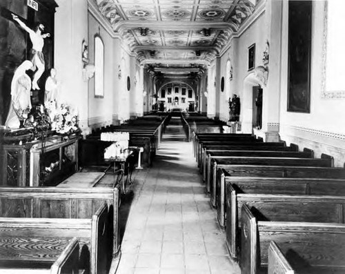 Plaza Church interior looking toward altar, Jesus on cross at left, tile floors and wood pews