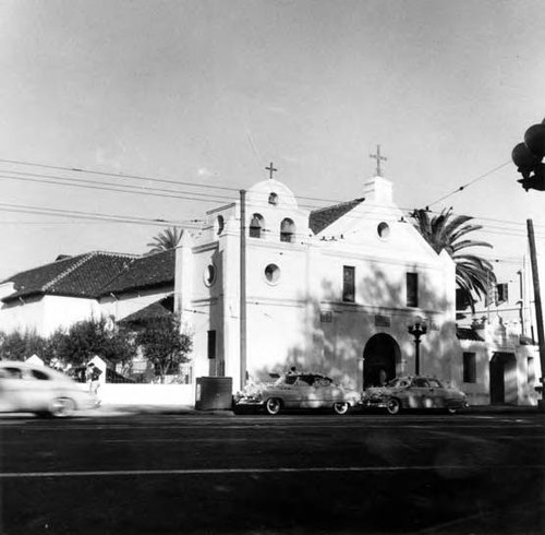 Angle shot of Plaza Church facade, with cars decorated for a wedding parked in front on Main Street