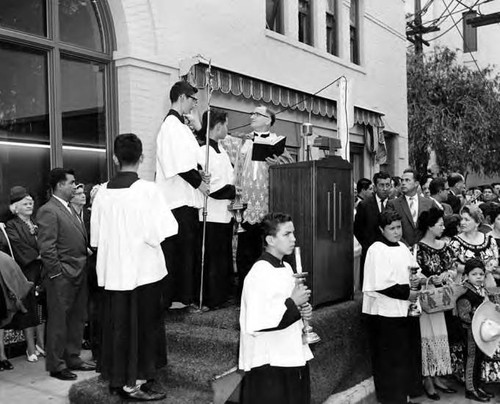 Priest at podium blessing the exterior of the Simpson building