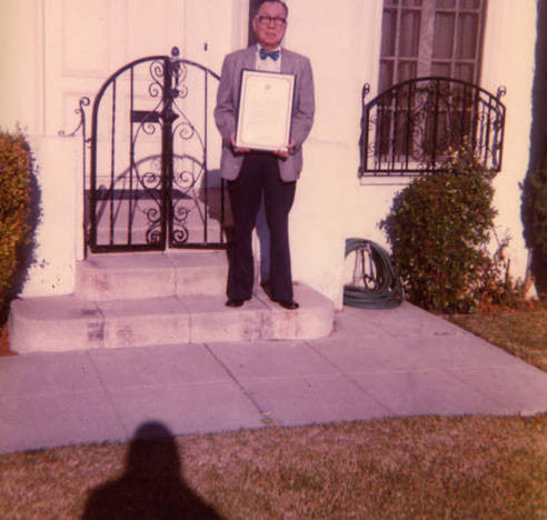 Stanley Chan holding an award in front of his home in Los Angeles