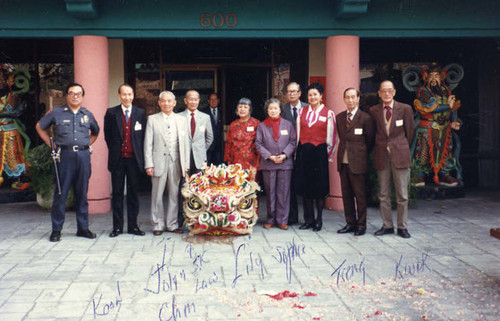 Group photo of Lily Lum Chan and board taken in front of 600 North Spring Street, Los Angeles