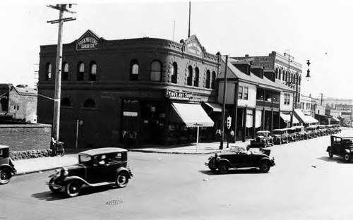 Lugo House on East side of Plaza, shows paved streets and cars and the Fook Wo Lung Curio Co. and Ying's Art Shop