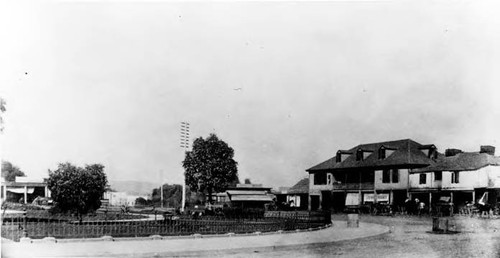 Exterior of Lugo House with horse and buggies in front. Part of the plaza is shown