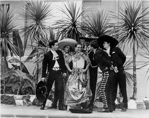 Woman in Mexican dress surrounded by men in Mexican riding garb