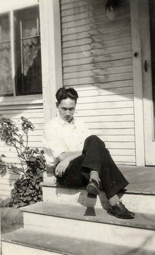 A young man, possibly Spencer Chan, seated on the porch steps of a white house (Spencer Chan Family)