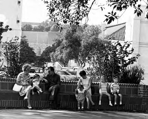 People sitting on brick benches around plaza