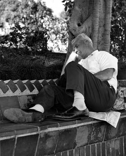 Man sleeping on brick bench near kiosko