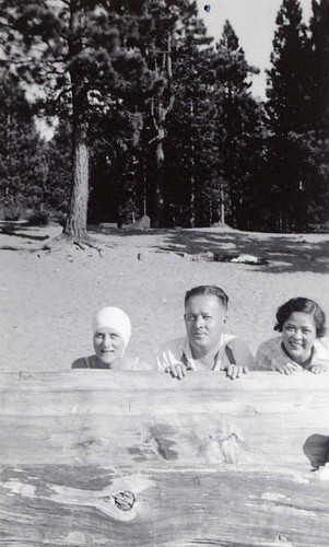 Three people peeping out from behind a large piece of wood. On the back of the photo it reads "Zephyrs Cove Lake Tahoe '35"