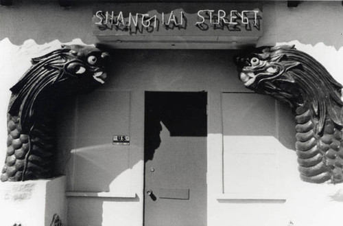 "Shanghai Street" neon sign framed by two dragon heads, remnants of China City