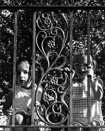 Little girls looking through grillwork