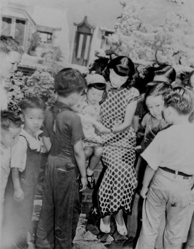 Anna May Wong surrounded by children, including Lily Mu and her brothers