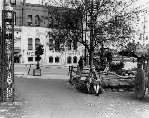 Photograph of a woman sitting and the La Olvera Cafe across the way