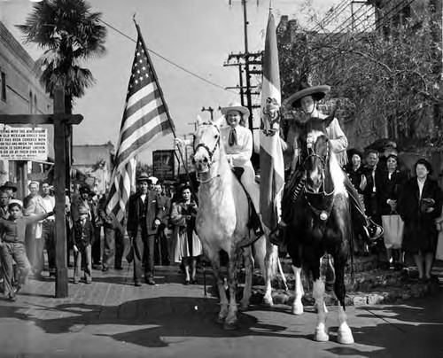 Riders with flags in front of cross at Blessing of the Animals