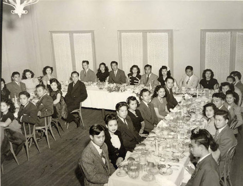 Large dinner gathering, at the table in the foreground on left, seventh from the front is Spencer Chan