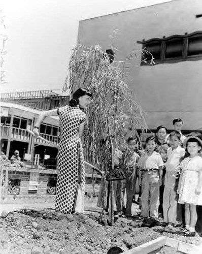 Anna May Wong digging a hole while children watch