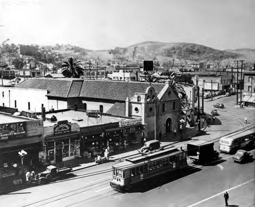 Overview of Church, Spanish store front signs, trolley car and bus on North Main street