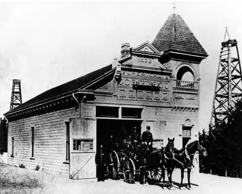 Los Angeles firehouse, Chemical Engine Co. #1. 125 Loma Drive or Belmont Avenue near First Street. William Glenn and George Bright are shown sitting on horse drawn fire cart. Pediment says 1892