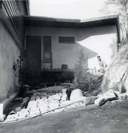 A man, possibly Spencer Chan, laying bricks for the front porch and walkway amid the construction in progress at the family house (Spencer Chan Family)