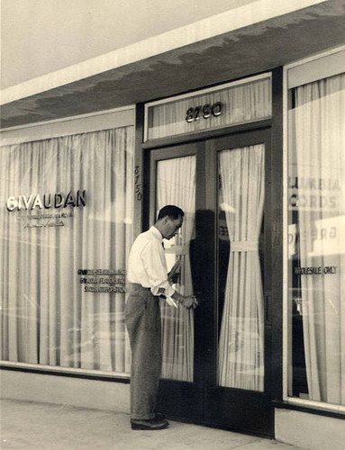 Man opening door to a store called "Givaudan," on the right the window says "Wholesale only"