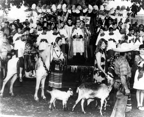 People with their animals passing by the priest and being blessed