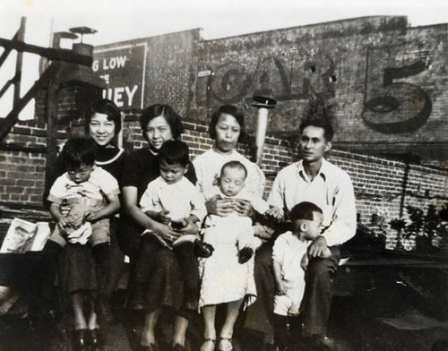 Howard Quon family sitting on a roof on Sanchez Street; pictures three women, one man and four children