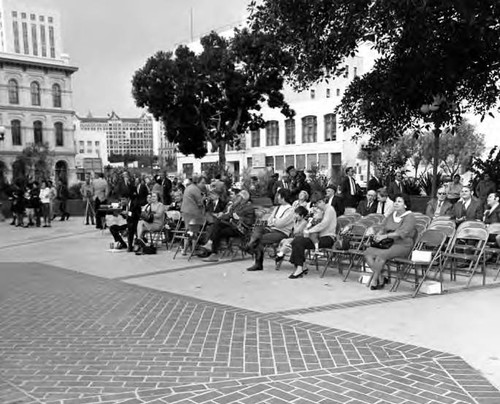 Crowd sitting in chairs watching a conert at the kiosko