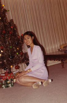 Susan Quan seated in front of a Christmas tree