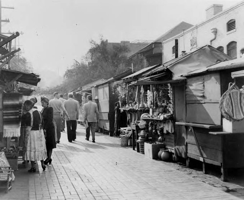 People walking in front of booths on Olvera Street