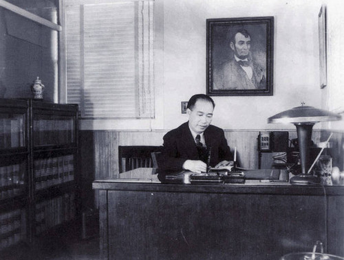 Albert Hing, insurance agent, at his desk