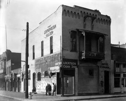 Photograph of Firehouse with three men standing at the corner, when it was the Cosmopolitan Saloon