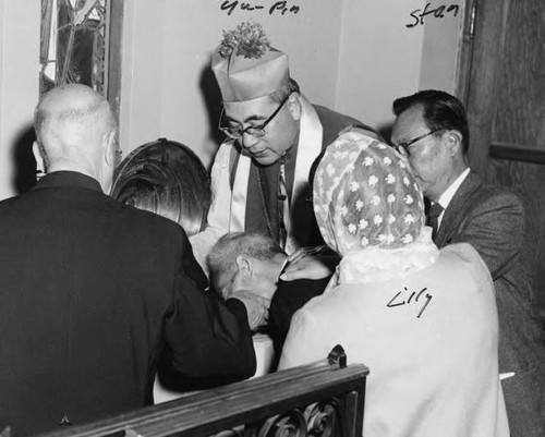 Photo of Cardinal Paul Yu Pin performing a baptism as Stanley and Lily Chan bear witness