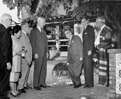 Olvera Street fountain with seven people standing at the fountain, one is Mario Valadez (on the far right)