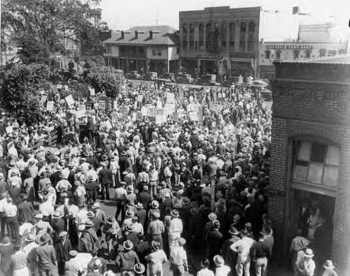 Plaza looking southwest. View is of men occupying the benches with the Vickrey/Brunswig Building in the background