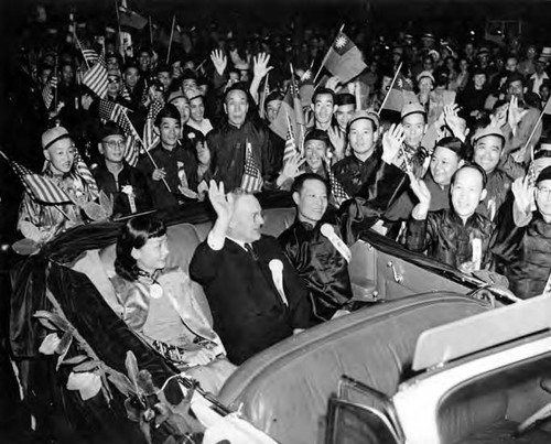 Photograph of Anna May Wong seated in a car with two other people