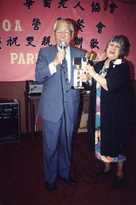 Lily Chan, president of the CCOA, awarding Wilbur Woo, a representative from Cathay Bank, who donated $10,000 to the CCOA Nutrition Department. The money came from the proceeds of a Golf Tournament. Wilbur Woo is in the middle and Lily Chan is on the right