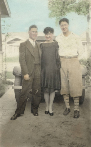 A man, Dorothy and Jake standing in a driveway in front of a car