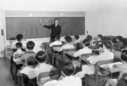 Stanley Chan teaches Chinese at the chalkboard, instructing a classroom of young students