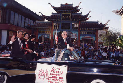 Poy Wong riding a black convertible representing the CCBA in the Los Angeles Golden Dragon Parade