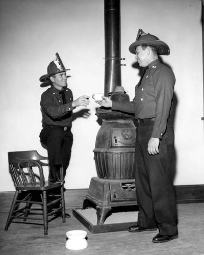 Two firemen by a pot bellied stove