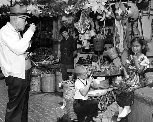 Man and boy taking pictures of little girl