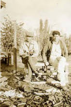 Jake Siu and another man sitting on a crate, when Flo and Rodney brought Mrs. de Lima down on tour of southern California