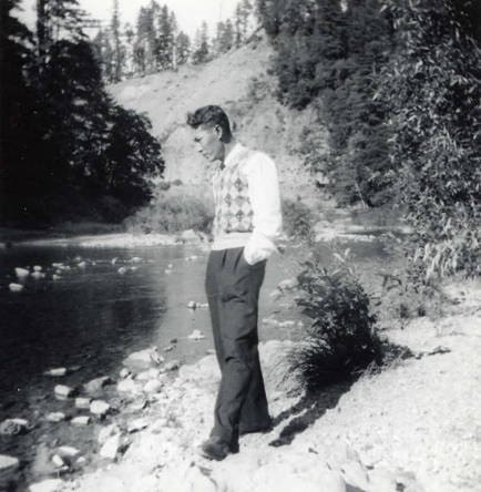 Photo of a man posed in front of a river. On the back of the photo it reads "Eel River, Redwood Feat- Calif."