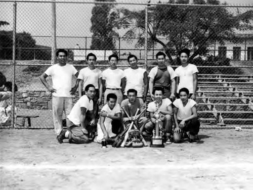 Baseball team photo with men in white shirts holding a trophy