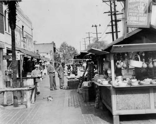 Three men and a kitten in standing in front of booths on Olvera Street