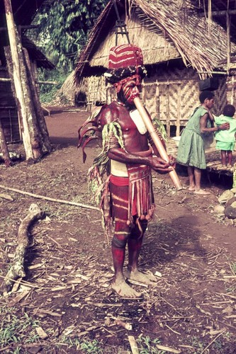 Local leader, in ceremonial dress, smokes a pipe