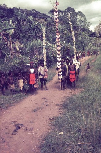 Participants arriving with pearlshells and Australian currency affixed to poles