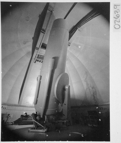 William C. Miller, on floor, looking through guidescope of 48-inch Schmidt telescope camera